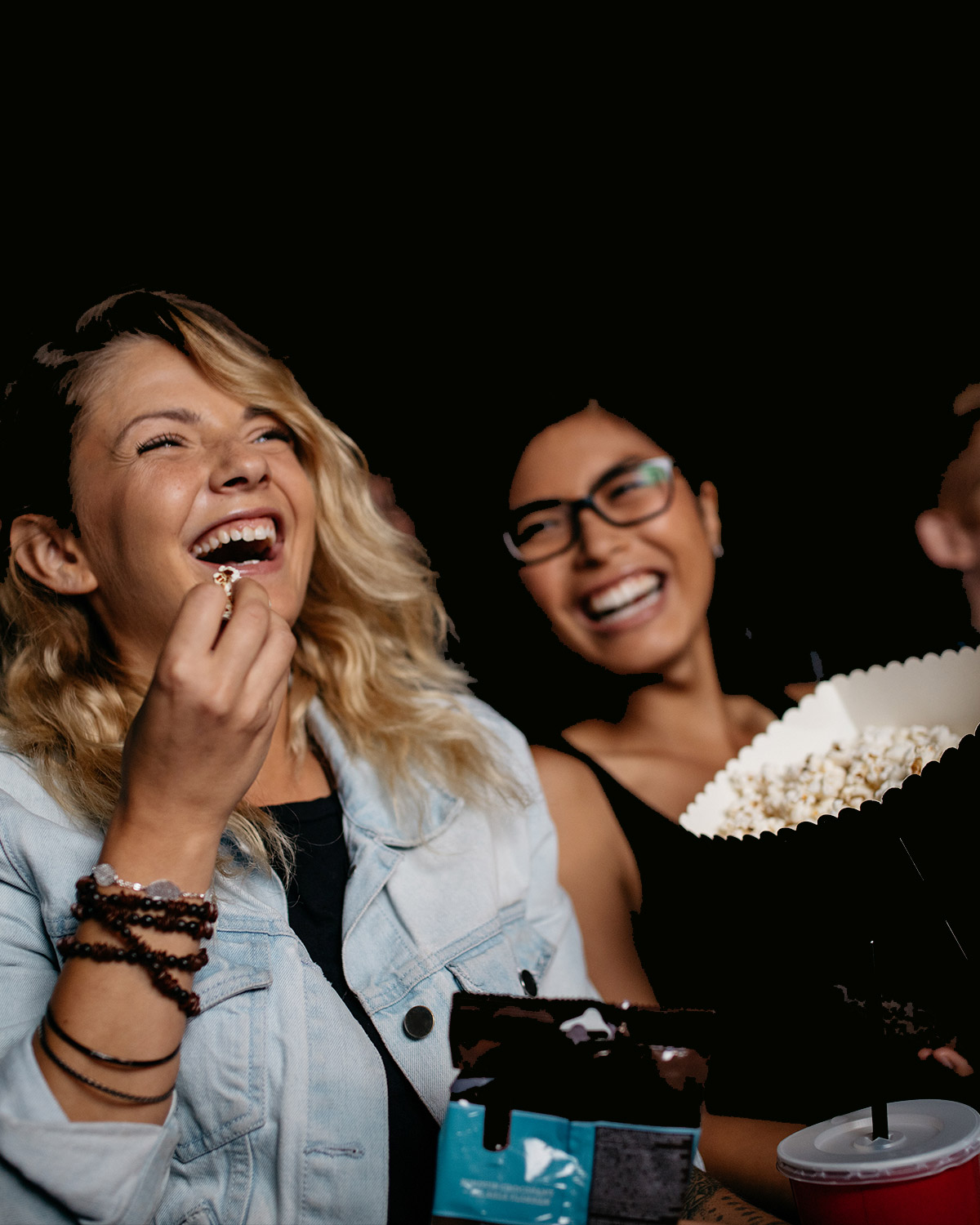 voksne som sitter i kinoseter ler og spiser popkorn